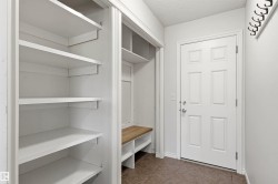 Entryway featuring tile flooring, a six-panel door, built-in shelving, a built-in bench, and wall-mounted coat hooks - 