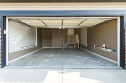 Spacious garage with painted walls, concrete flooring, and an interior staircase - 