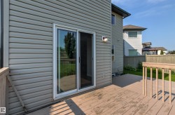 Rear deck featuring a sliding glass door, light-colored siding, and a wooden railing - 
