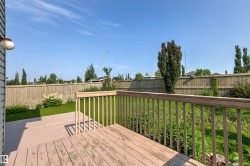 Rear deck with wood railing and composite decking, extending to a manicured lawn area - 