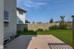 Spacious backyard featuring a composite deck, expansive lawn, and mature perimeter fencing - 