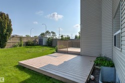 Expansive backyard featuring a large composite deck with natural wood railing, a manicured lawn, a privacy fence, and a detached storage shed - 