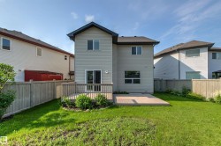 Rear exterior of a two-story residence with light-colored horizontal siding and a dark shingle roof - 