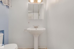 Pedestal sink with a two-handle faucet and a wall-mounted medicine cabinet - 