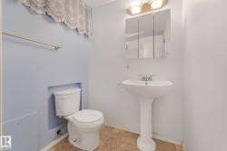 Bathroom featuring a white pedestal sink with a dual-handle faucet, a triple mirrored medicine cabinet, and overhead vanity lighting - 
