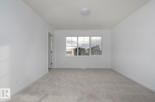 Room featuring light gray carpeting, white painted walls, and a multi-pane window with white trim - 3888 Wren Crescent, Edmonton, AB 