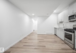 Modern kitchen featuring stainless steel appliances, light gray cabinetry, white subway tile backsplash, and composite countertops - 