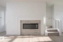 Modern electric fireplace with a light-toned brick surround, white mantel, and wood-finish flooring - 