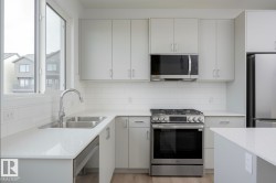 Modern kitchen with light grey cabinetry, white subway tile backsplash, and stainless steel appliances - 