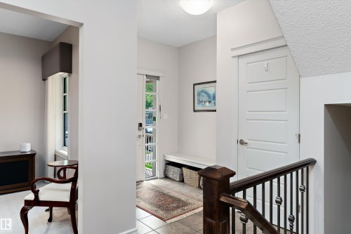 Entryway featuring a front door with glass panels, tile flooring, and a built-in bench - 1097 Armitage Crescent, Edmonton, AB 