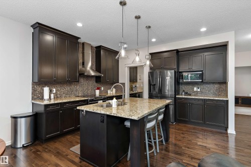 Kitchen featuring dark wood cabinetry, light granite countertops, and mosaic tile backsplash - 1097 Armitage Crescent, Edmonton, AB 