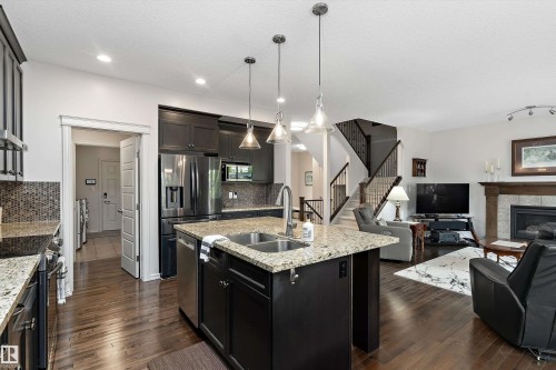 Open-concept kitchen featuring dark wood cabinetry, granite countertops, and stainless steel appliances - 1097 Armitage Crescent, Edmonton, AB 