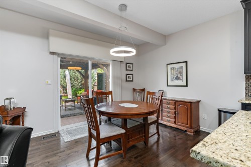 Dining area featuring dark wood-finish flooring and a contemporary circular pendant light fixture - 1097 Armitage Crescent, Edmonton, AB 