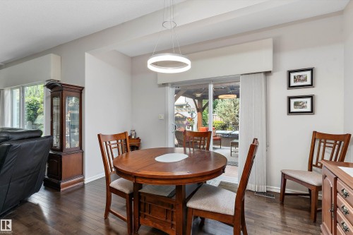 Dining area with dark wood-finish flooring, a contemporary circular light fixture, and a glass sliding door providing access to the exterior space - 1097 Armitage Crescent, Edmonton, AB 