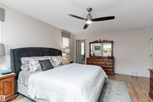 Spacious room featuring wood-finish flooring, a contemporary ceiling fan with integrated lighting, and neutral wall tones - 1097 Armitage Crescent, Edmonton, AB 