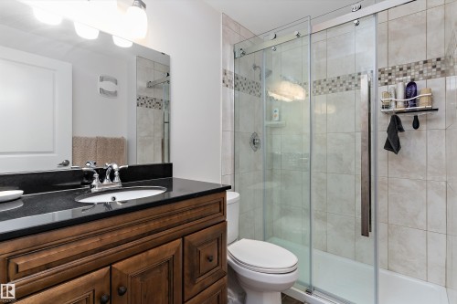 Bathroom featuring a wood-finish vanity with a built-in sink, a dark countertop, and a chrome faucet - 1097 Armitage Crescent, Edmonton, AB 