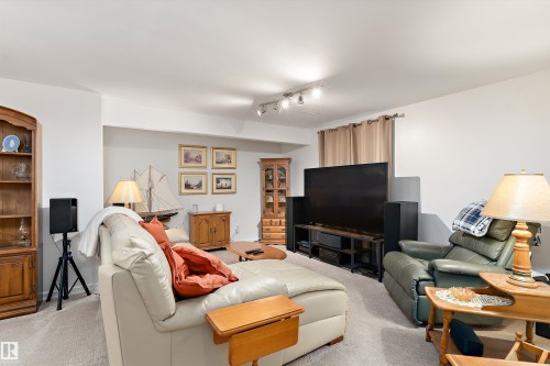 Carpeted living area featuring track lighting, light-toned walls, and a recessed ceiling section - 1097 Armitage Crescent, Edmonton, AB 