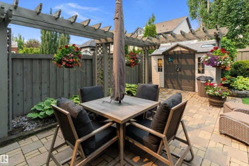 Paved patio area featuring a pergola, a storage shed, and perimeter fencing - 1097 Armitage Crescent, Edmonton, AB 