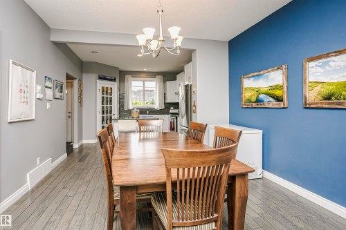 Dining area featuring wood-finish flooring, a contemporary chandelier, two-tone wall paint, and white baseboards - 11619 125 Street, Edmonton, AB 