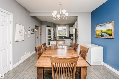 Open-concept dining area featuring wood-finish flooring and a contemporary chandelier - 11619 125 Street, Edmonton, AB 