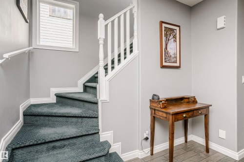Carpeted staircase with white balusters, white handrail, and a window with blinds - 11619 125 Street, Edmonton, AB 