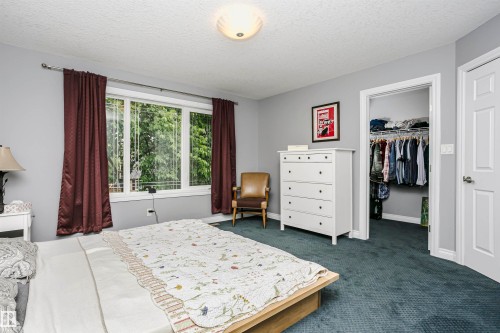 Bedroom featuring a large window, wall-to-wall carpeting, and a built-in closet with wire shelving - 11619 125 Street, Edmonton, AB 