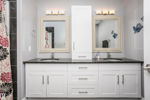 Dual vanity with white cabinetry, dark speckled countertop, and integrated sinks - 11619 125 Street, Edmonton, AB 