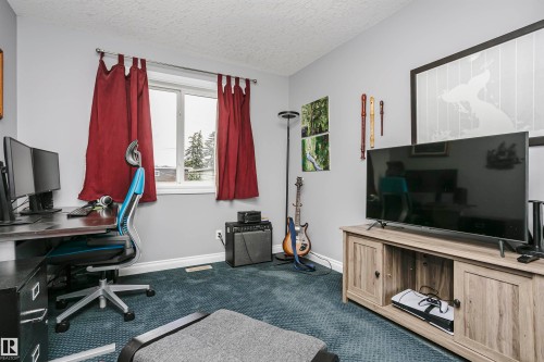 Bedroom presently used as office.Room featuring light gray walls, textured blue carpeting, a white-framed window, and white baseboards - 11619 125 Street, Edmonton, AB 