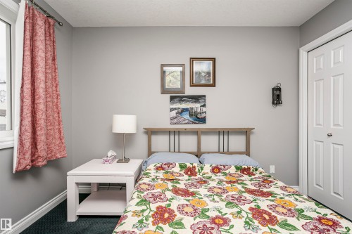 Bedroom featuring light gray walls, a window with white trim, dark carpeting, and a white paneled door - 11619 125 Street, Edmonton, AB 