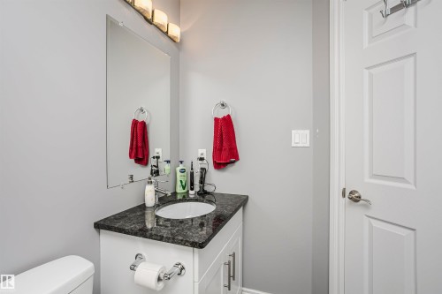 Vanity with dark countertop and undermount sink, framed by a wall-mounted mirror - 11619 125 Street, Edmonton, AB 
