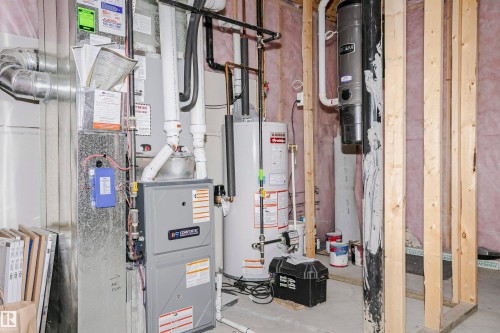 Utility area featuring a furnace, water heater, and central vacuum system with exposed wood framing - 11619 125 Street, Edmonton, AB 