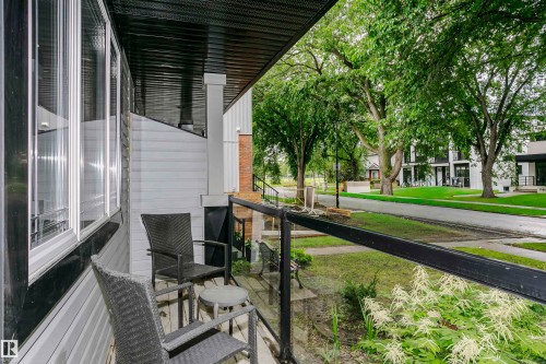 Covered front porch featuring a glass railing, dark-stained ceiling, and light-colored siding - 11619 125 Street, Edmonton, AB 