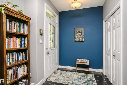 Entryway featuring dark tile flooring, a white paneled door with decorative glass, and a transom window - 11619 125 Street, Edmonton, AB 