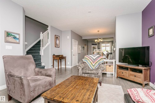 Living area featuring wood-finish flooring, a carpeted staircase with white balusters, and a recessed ceiling - 11619 125 Street, Edmonton, AB 