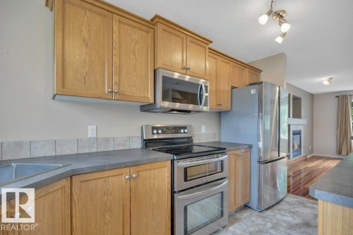 Spacious kitchen includes upgraded appliances and a raised eating bar plus a pantry. - 7948 13 Avenue, Edmonton, AB 