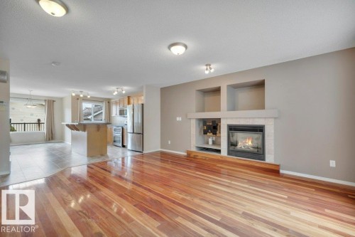 Beautiful and spacious living room accented with Tigerwood hardwood, gas fireplace, and built in entertainment niches with a built in bar area with extra cabinets. - 7948 13 Avenue, Edmonton, AB 