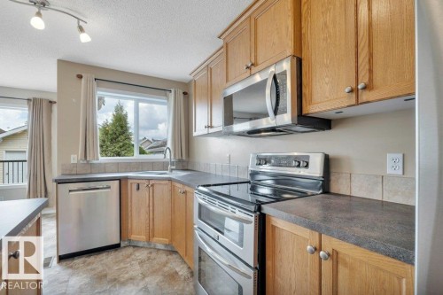 Spacious kitchen includes upgraded appliances and a raised eating bar plus a pantry. - 7948 13 Avenue, Edmonton, AB 