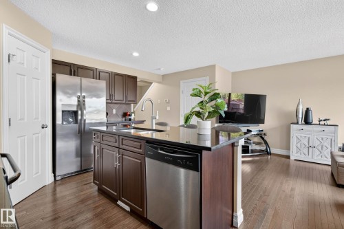 Kitchen island featuring a black countertop and integrated sink with a stainless steel faucet - 12119 167A Avenue, Edmonton, AB 