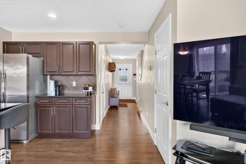 Kitchen with dark wood-finish cabinetry, stainless steel refrigerator, and dark countertop with tiled backsplash - 12119 167A Avenue, Edmonton, AB 