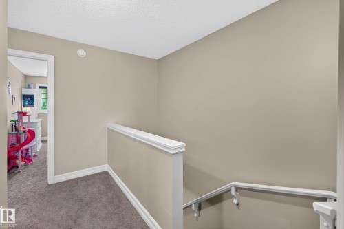 Upper-level hallway with carpet flooring, neutral paint, white trim, and a white stair railing - 12119 167A Avenue, Edmonton, AB 
