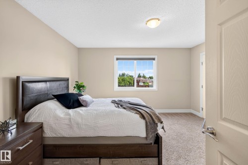 Neutral-toned bedroom featuring a single window, textured carpet, and a light-colored ceiling - 12119 167A Avenue, Edmonton, AB 