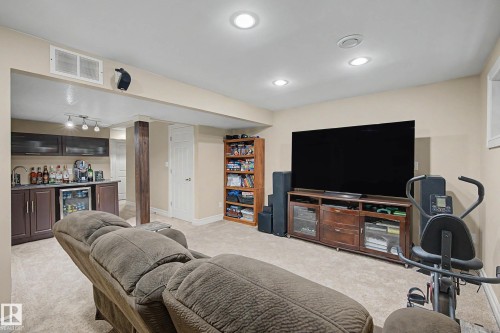 Finished lower level featuring recessed lighting, a built-in wet bar with dark cabinetry and a beverage refrigerator, and a dedicated entertainment area - 12119 167A Avenue, Edmonton, AB 