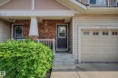 Entryway featuring a dark paneled door, stone facade accents, concrete steps, and a white porch railing - 12119 167A Avenue, Edmonton, AB 