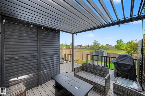 Expansive outdoor deck featuring a louvered pergola with integrated lighting, wood-finish decking, and black metal railings - 12119 167A Avenue, Edmonton, AB 