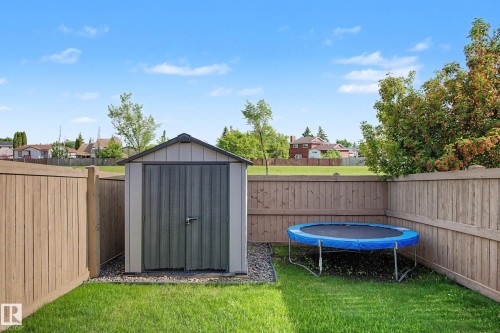 Private backyard featuring a storage shed on a gravel base, bordered by wood fencing and a manicured lawn - 12119 167A Avenue, Edmonton, AB 