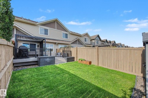 Fenced backyard featuring a wooden deck with a black pergola, green lawn, and a small storage shed - 12119 167A Avenue, Edmonton, AB 