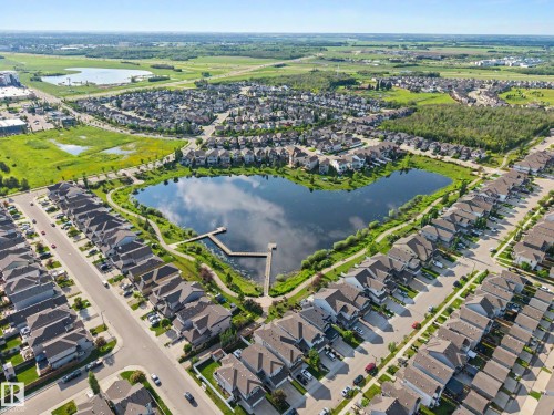 Aerial perspective of a structured residential community featuring a prominent central pond with a dock - 12119 167A Avenue, Edmonton, AB 