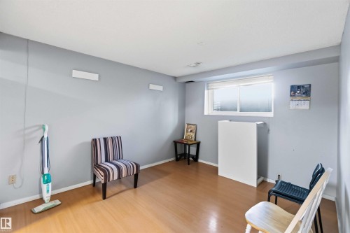 Room featuring wood-finish flooring, a white window frame with horizontal blinds, and light gray walls - 8819 29 Avenue, Edmonton, AB 