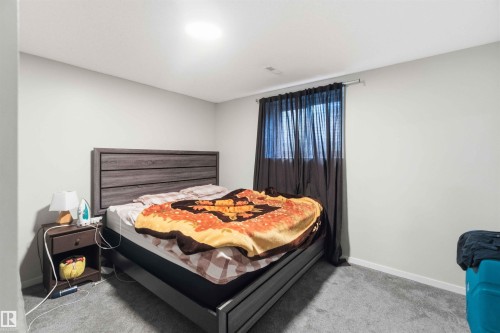 Bedroom featuring neutral wall paint, gray carpeting, a window with dark curtains, and a ceiling light fixture - 8819 29 Avenue, Edmonton, AB 