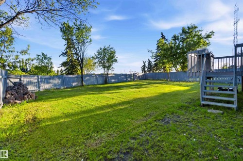 Expansive green lawn with mature trees and a perimeter fence - 8819 29 Avenue, Edmonton, AB 